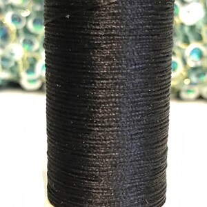 May include: A spool of black thread for sewing or embroidery.