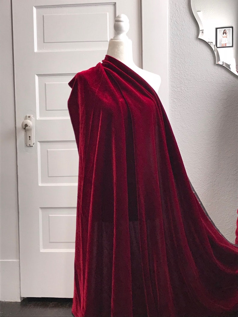 May include: A deep red velvet fabric draped over a mannequin. The fabric is soft and luxurious, with a rich, velvety texture.