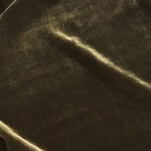May include: Close-up of olive green velvet fabric with soft folds and highlights. The plush material has a subtle sheen, creating a luxurious texture. Ideal for apparel, upholstery, or craft projects.