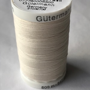 May include: A spool of white Gütermann thread with a label that reads "Col. 22", "Gütermann", "Germany", and "077780006300". The spool is labeled with "500 m - 541" on the bottom.