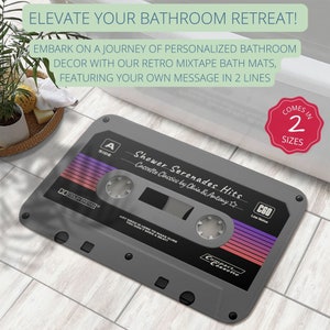 K&ouml;nnte beinhalten: Eine graue Badematte in Form einer Kassette mit dem Text "Shower Serenades Hits" und "Cassette Classics by Ohia & Antony". Die Matte hat ein rot-violettes Design und den Text "C60 Low Noise" und "Compact Cassette".