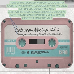 K&ouml;nnte beinhalten: Eine rosa und blaue Kassetten-Badematte mit dem Text "Bathroom Mix tape Vol. 2" und "Shower jams collection by Daniel & Mika (02/15/23)". Die Matte hat einen Barcode und den Text "294896" und "CHF90".