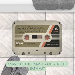 K&ouml;nnte beinhalten: Eine beige und braune Kassetten-Badematte mit dem Text "Shower Mixtape 12.08.21 Bathtub Melodies by Michael & Ava" und "E60 ULTRA CHROME ART BROZ RECORDS THE SOUNDTRACK OF LIFE! STEREO DO DOLBY SYSTEM" darauf gedruckt. Die Matte ist ein Beispiel f&uuml;r die kleine Gr&ouml;&szlig;e, die 61 x 43 cm misst.