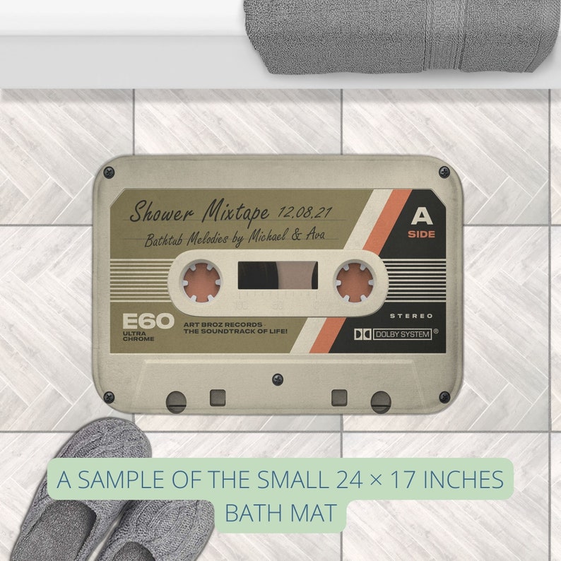 K&ouml;nnte beinhalten: Eine beige und braune Kassetten-Badematte mit dem Text "Shower Mixtape 12.08.21 Bathtub Melodies by Michael & Ava" und "E60 ULTRA CHROME ART BROZ RECORDS THE SOUNDTRACK OF LIFE! STEREO DO DOLBY SYSTEM" darauf gedruckt. Die Matte ist ein Beispiel f&uuml;r die kleine Gr&ouml;&szlig;e, die 61 x 43 cm misst.