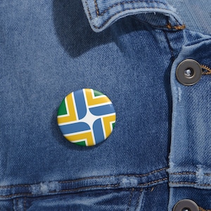 May include: A round button with the flag of Portland, Oregon. The flag is a white star in the center of a blue, yellow, and green geometric design.