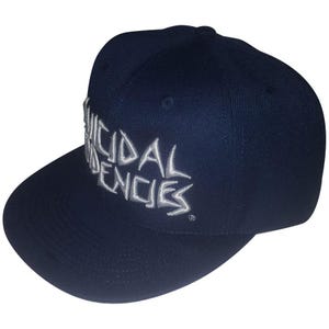 Könnte beinhalten: Marineblaue Baseballkappe mit flachem Schirm, bestickt mit dem weißen Schriftzug "SUICIDAL TENDENCIES". Die Kappe hat eine strukturierte Krone und ist für den lässigen Gebrauch konzipiert.