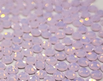 May include: A close-up view of a large quantity of small, iridescent, light purple, faceted rhinestones.