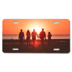 May include: Silhouettes of five people walking on a beach at sunset. The sky is a vibrant orange and the sun is setting behind them.