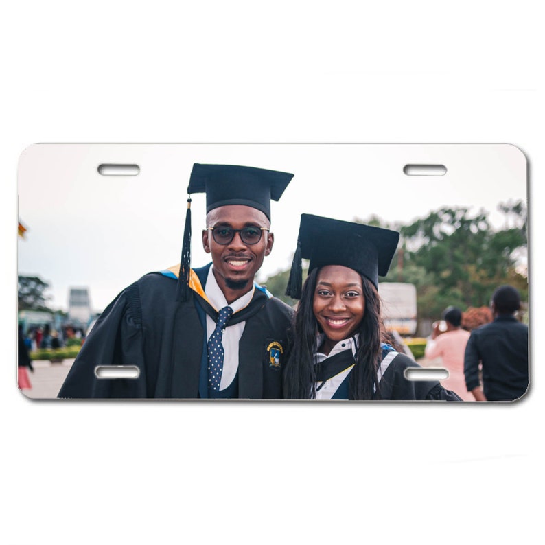 May include: Two people wearing black graduation gowns and caps, smiling at the camera. The person on the left is wearing a blue tie and glasses. The person on the right has long black hair.