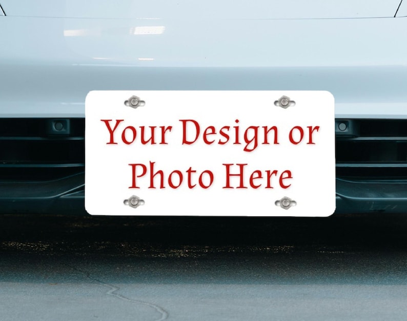 May include: White license plate with four silver mounting screws. The plate has red text that reads "Your Design or Photo Here."