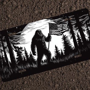 May include: Black and white illustration of Bigfoot holding an American flag in a forest setting with a full moon in the background.