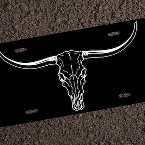 May include: Black license plate with a white outline of a bull skull with horns.