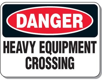 Può includere: Un cartello bianco e nero con un ovale rosso che dice "DANGER" in lettere bianche. Il cartello dice anche "HEAVY EQUIPMENT CROSSING" in lettere nere.