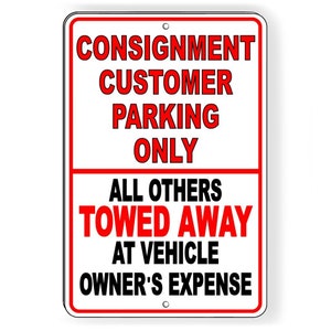 May include: White sign with red text that reads "Consignment Customer Parking Only. All Others Towed Away At Vehicle Owner's Expense."