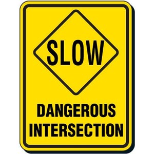 May include: A yellow diamond-shaped road sign with black lettering that reads "SLOW" and the text "DANGEROUS INTERSECTION" below.