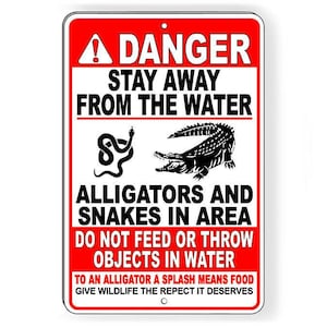 Peut inclure: Un panneau d'avertissement rouge et blanc avec un point d'exclamation noir. Le panneau indique "Danger Restez à l'écart de l'eau Alligators et serpents dans la zone Ne nourrissez pas et ne jetez pas d'objets dans l'eau Pour un alligator, une éclaboussure signifie de la nourriture Donnez à la faune le respect qu'elle mérite"