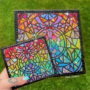 May include: Two framed diamond painting art pieces with a rainbow stained glass design. The smaller piece is in front of the larger piece. The text "Cleola_Creations" is in the bottom right corner of the image.