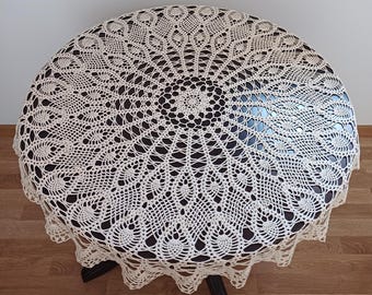 May include: A white crocheted tablecloth with a circular design. The tablecloth features a delicate, intricate pattern with a central motif.
