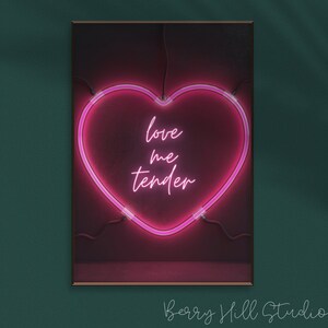 May include: A pink neon heart-shaped sign with the words "love me tender" inside. The sign is on a dark red background.
