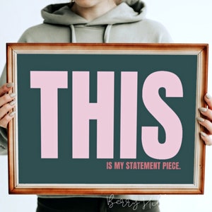 May include: A framed print with a dark teal background and the word "THIS" in large, pink letters. The text "IS MY STATEMENT PIECE." is written in smaller, white letters below the word "THIS".