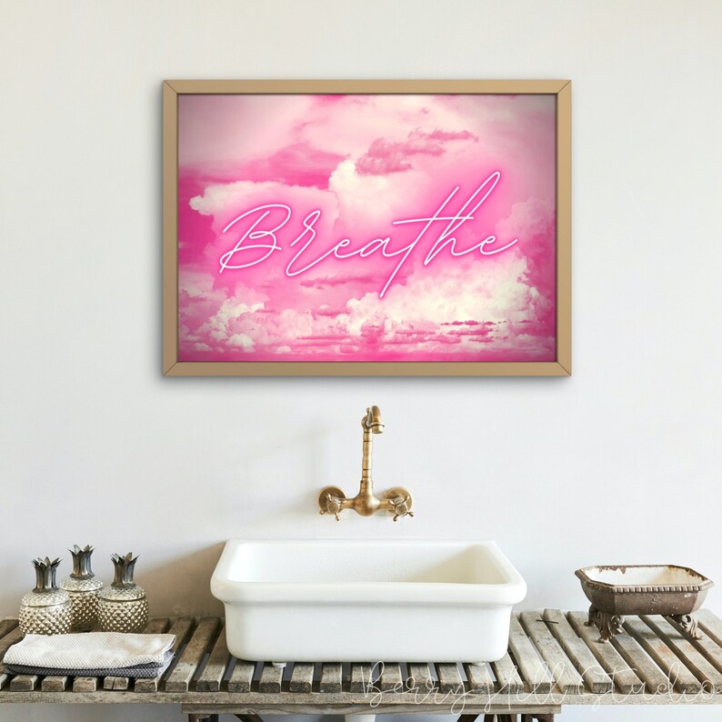 May include: A framed print with a pink and white cloudy sky background and the word "Breathe" in pink neon lettering.