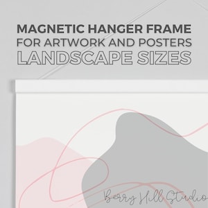 May include: White magnetic hanger frame for artwork and posters. The frame is hanging on a white wall and has a white background with abstract pink and gray shapes and the text "Berry Hill Studio".