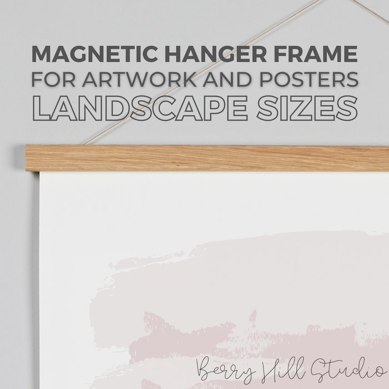 May include: A wooden magnetic hanger frame for artwork and posters. The frame is hanging on a wall and has a white background with a light pink abstract design. The text "Berry Hill Studio" is visible at the bottom of the image.