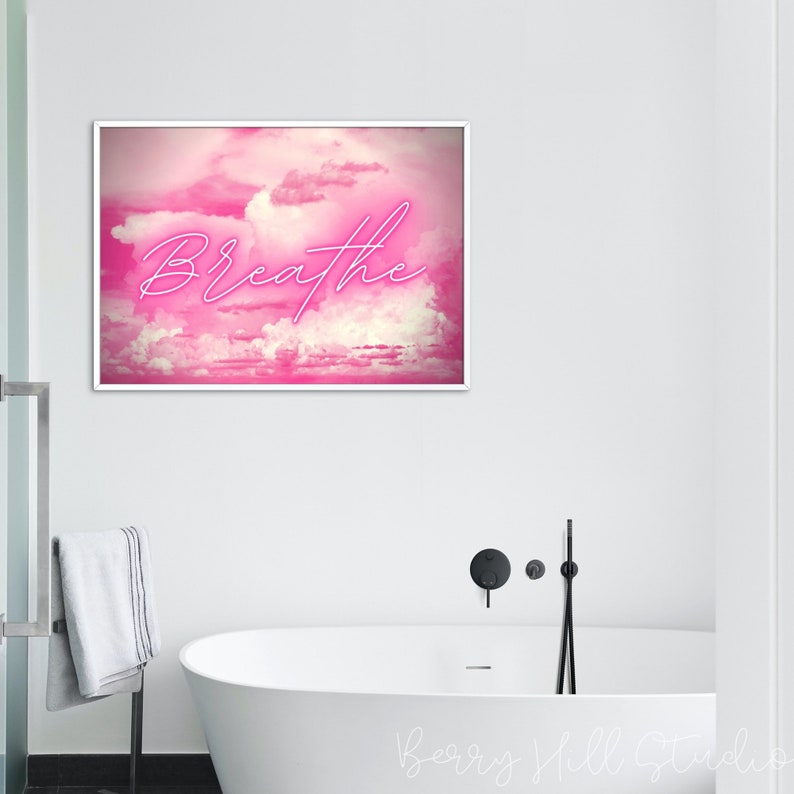 May include: A pink and white abstract art print with the word "Breathe" in neon pink lettering. The print is framed in a white frame and is hanging on a white wall.