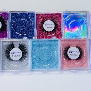 May include: A collection of ten false eyelashes in clear plastic cases. Each case has a glittery background in various colors, including purple, blue, pink, and gold. The eyelashes are black and fluffy, with a white label that reads "Purple Plush Eyelashes".
