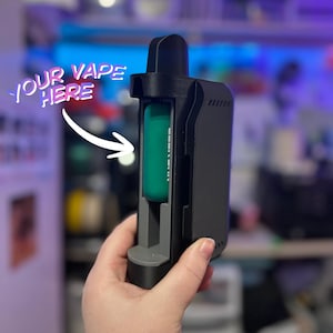 Peut inclure: Un &eacute;tui de vape noir et gris avec une cartouche de vape turquoise &agrave; l'int&eacute;rieur. Le texte "YOUR VAPE HERE" est &eacute;crit en rose et blanc au-dessus de l'&eacute;tui avec une fl&egrave;che blanche pointant vers la cartouche de vape.