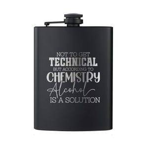 May include: Black stainless steel flask with a hinged cap. The flask has the text "NOT TO GET TECHNICAL BUT ACCORDING TO CHEMISTRY Alcohol IS A SOLUTION" in white lettering. The flask is rectangular and has a matte finish.
