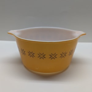 Puede incluir: Un tazón mezclador de cerámica amarillo con un interior blanco y un patrón geométrico negro alrededor del borde.