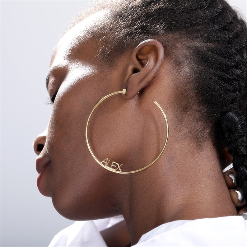 May include: Gold hoop earrings with the name "ALEX" spelled out in the hoop.
