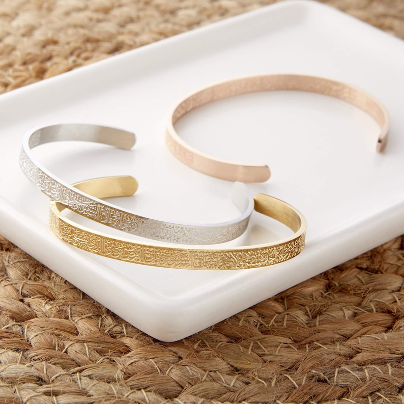 May include: Three gold, silver, and rose gold bracelets with an intricate engraved pattern. The bracelets are stacked on a white surface.