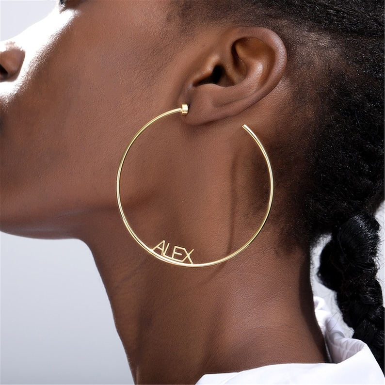 May include: Gold hoop earrings with the name "ALEX" spelled out on the hoop.