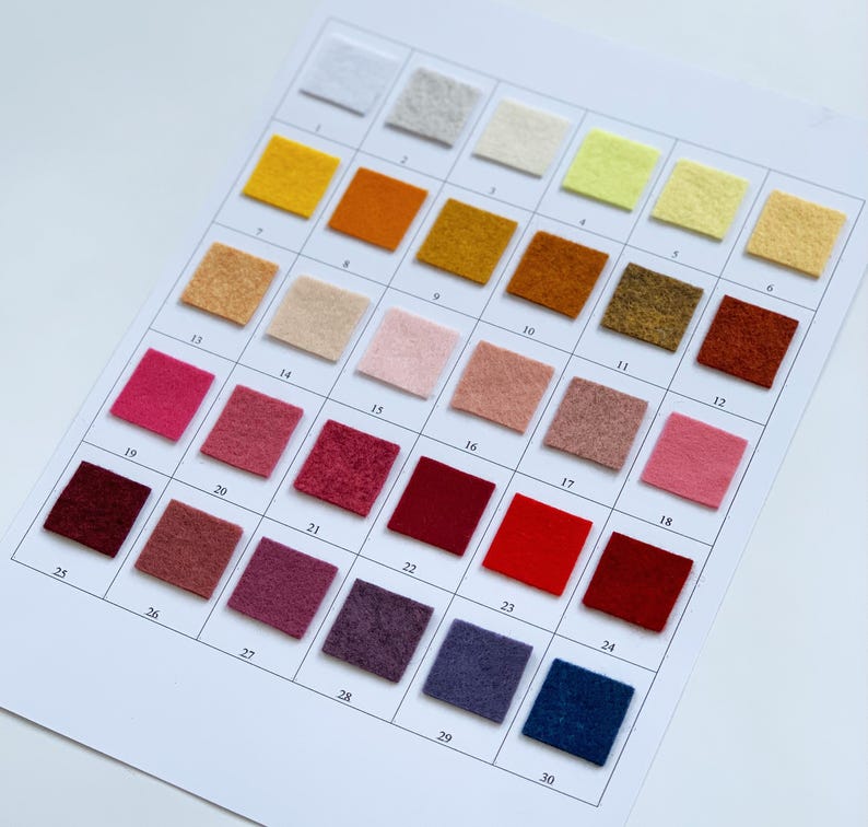May include: A color chart featuring 30 small, square felt swatches in a variety of colors, including white, yellow, orange, brown, pink, red, and blue. The swatches are arranged in a grid and numbered for easy reference. The chart is on a white background.