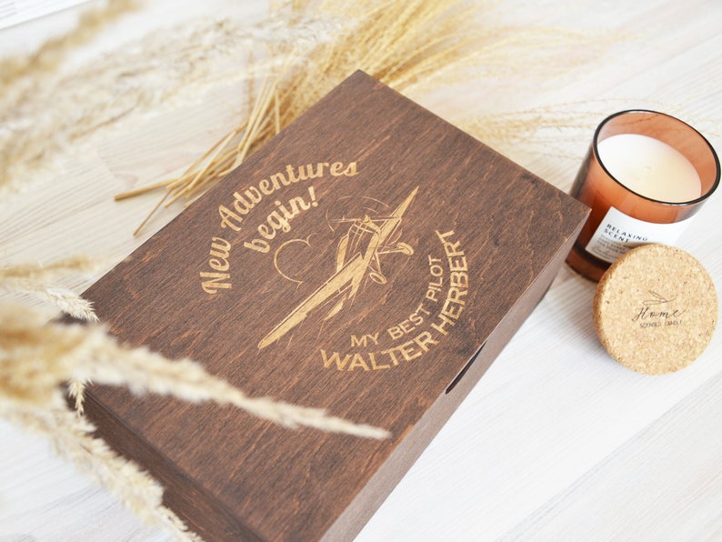 May include: A dark brown wooden box with an engraved design of a plane and the text "New Adventures begin! My Best Pilot Walter Herbert".