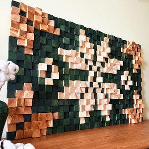 May include: A large, rectangular wooden wall art piece. The artwork features a mosaic of small, square wooden blocks in varying shades of green and natural wood tones. The design creates a textured, three-dimensional effect, suitable for home decor.