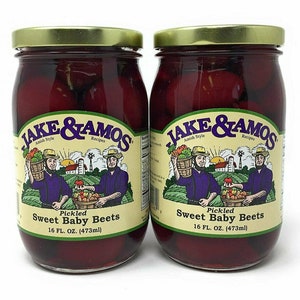 May include: Two glass jars of pickled sweet baby beets, each labeled "JAKE & AMOS Amish Style Recipes Pickled Sweet Baby Beets 16 FL. OZ. (473ml)". The jars are filled with red beets in a clear liquid.