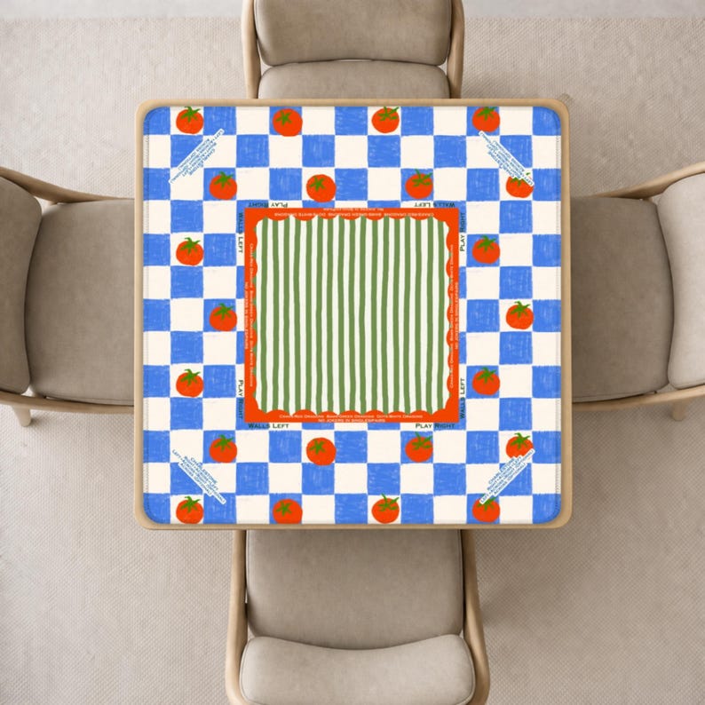 May include: Square table with a blue and white checkered pattern, orange tomatoes, and green and white striped center. The table has a wooden frame and is surrounded by four beige chairs. Text on the table reads "BALLS LEFT" and "PLAY RIGHT".