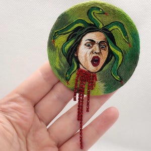 Hand-embroidered Medusa Gorgon brooch with serpent hair and blood-red details. A bold statement piece inspired by classical mythology