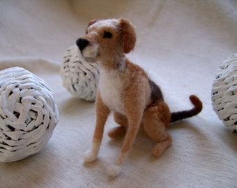 May include: A hand-felted brown and white dog figurine with a white chest and brown and black markings. The figurine is sitting on a white fabric surface.