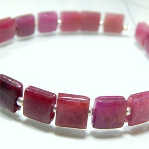 May include: A bracelet made of square-shaped pink gemstones, separated by silver beads.