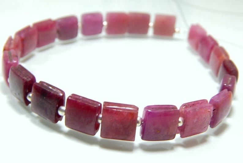 May include: A bracelet made of square-shaped pink gemstones, separated by silver beads.