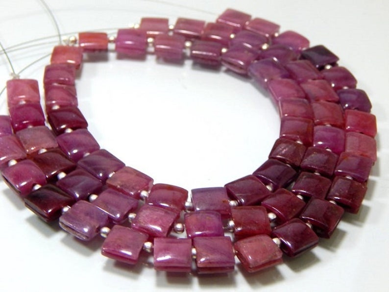 May include: A strand of square-shaped ruby beads in shades of pink and purple. The beads are strung on a silver wire.