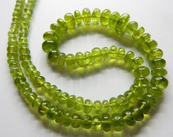 May include: A strand of green peridot beads. The beads are round and have a smooth, polished finish.
