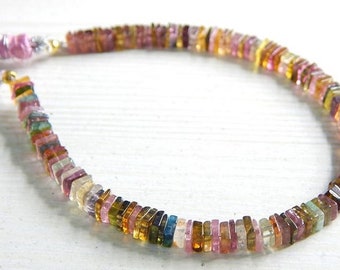 May include: A strand of multi-colored square-shaped gemstone beads with a pink tassel on each end.