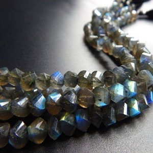 May include: A strand of faceted labradorite gemstone beads in shades of grey, blue, and green. The beads have an iridescent sheen.