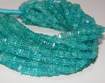May include: A strand of turquoise blue gemstone beads, each bead is faceted and has a rectangular shape.