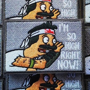 Pode incluir: Um personagem de desenho animado com bigode e uma faixa de cabeça diz "Estou tão chapado agora!" em um patch bordado cinza e branco.